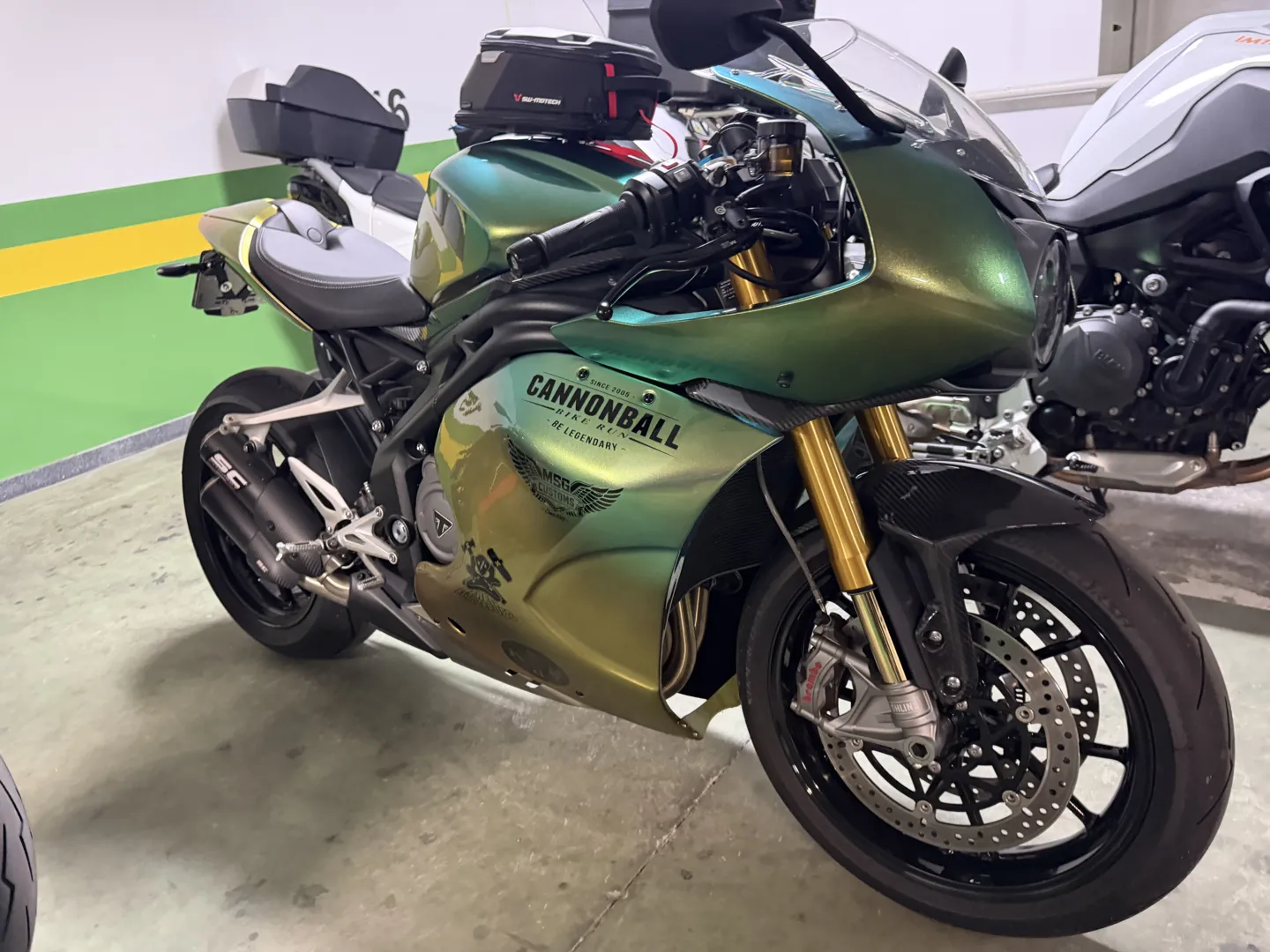 Green Triumph sportsbike in Cannonball livery parked in the hotel garage in Santander