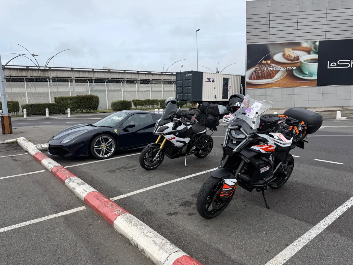 Two adventure motorcycles parked outside the cafe at the Le Shuttle terminal in Calais