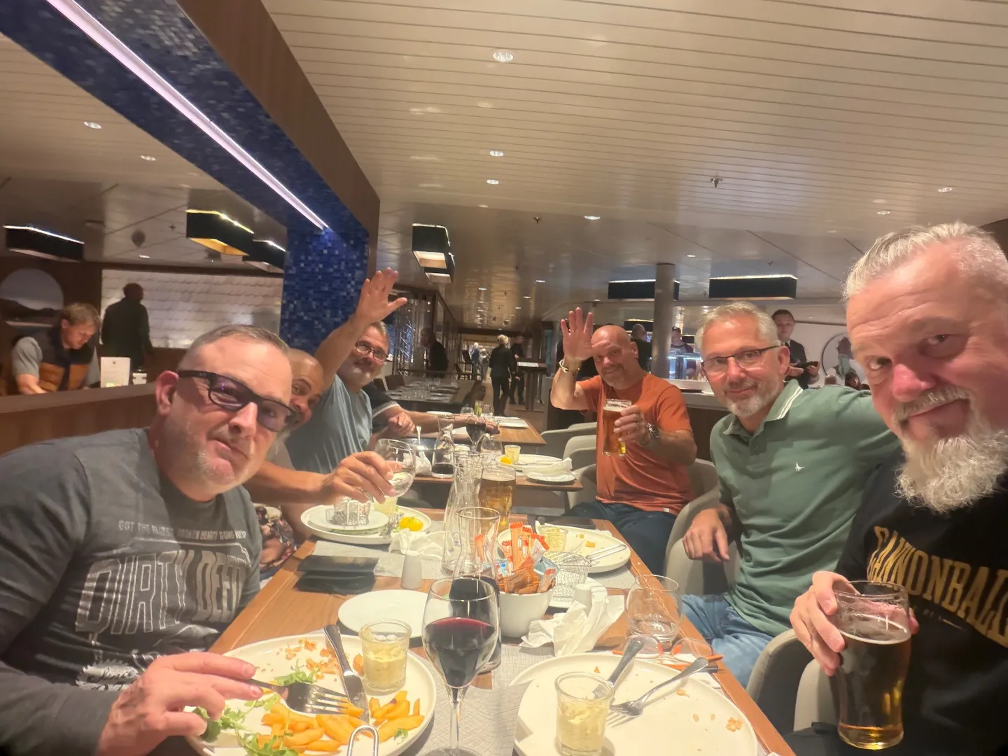 Cannonball riders raising drinks around a dinner table on the ferry from Portsmouth to Bilbao