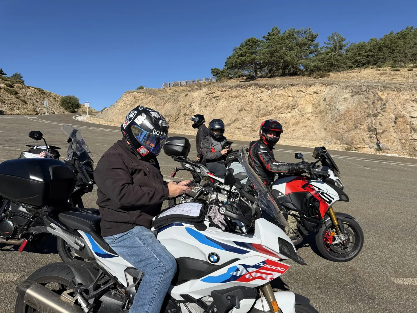 Riders pulled over at a mountain pass checking the road book and navigation on their bikes