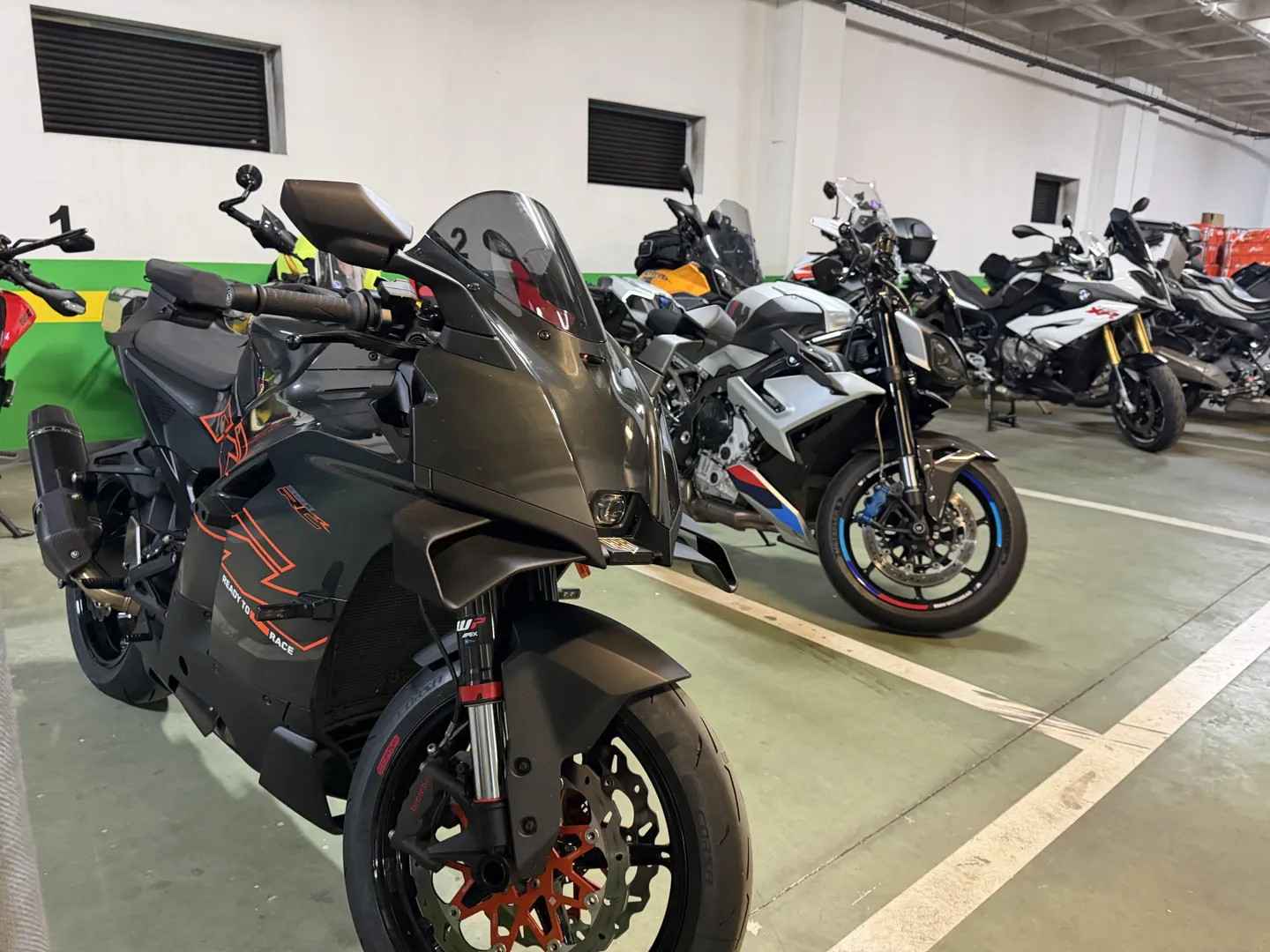 Black KTM sportsbike and a row of motorcycles filling the hotel garage in Santander