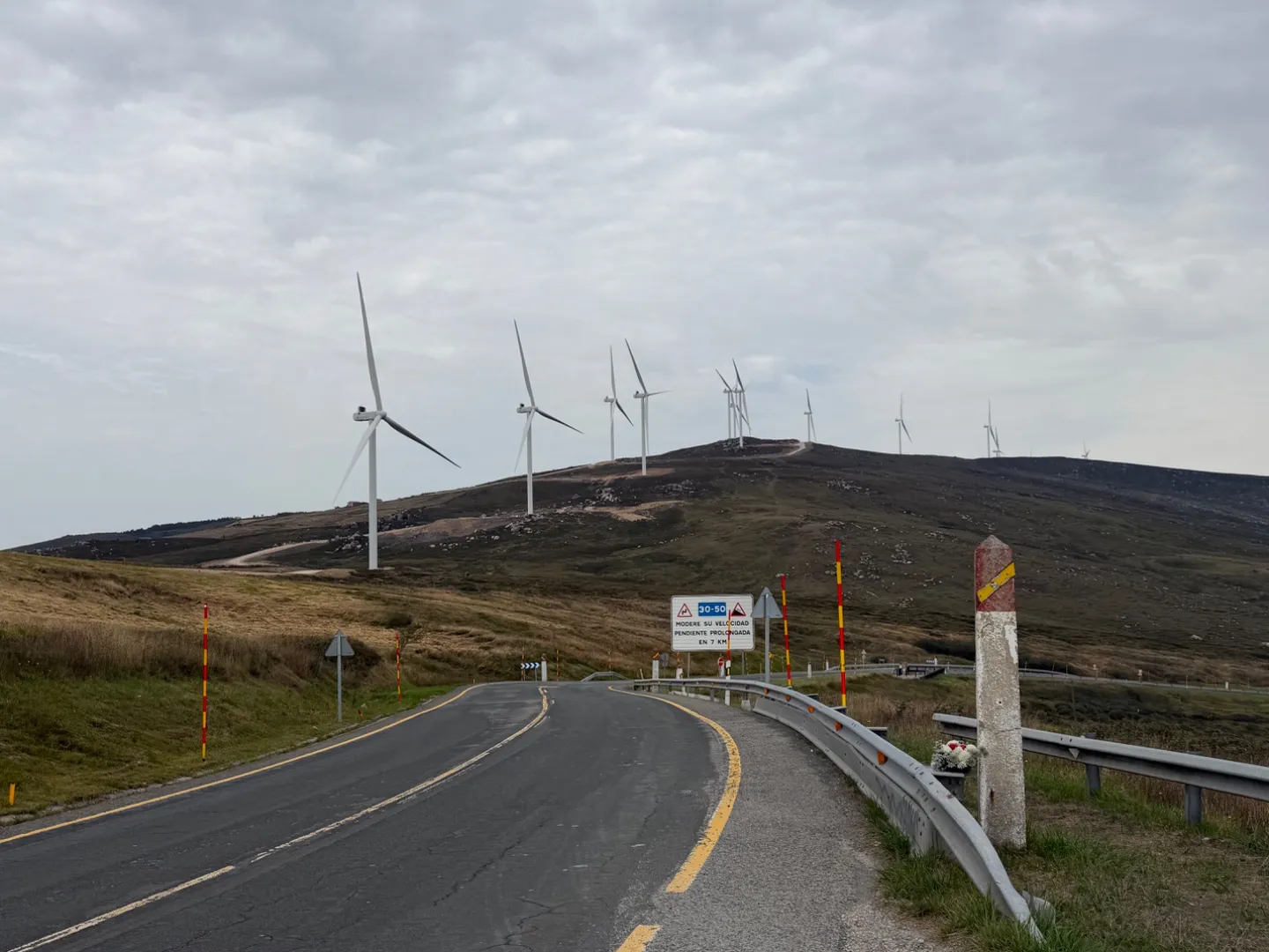 Mountain road curving past a ridge of wind turbines between Bilbao and Santander