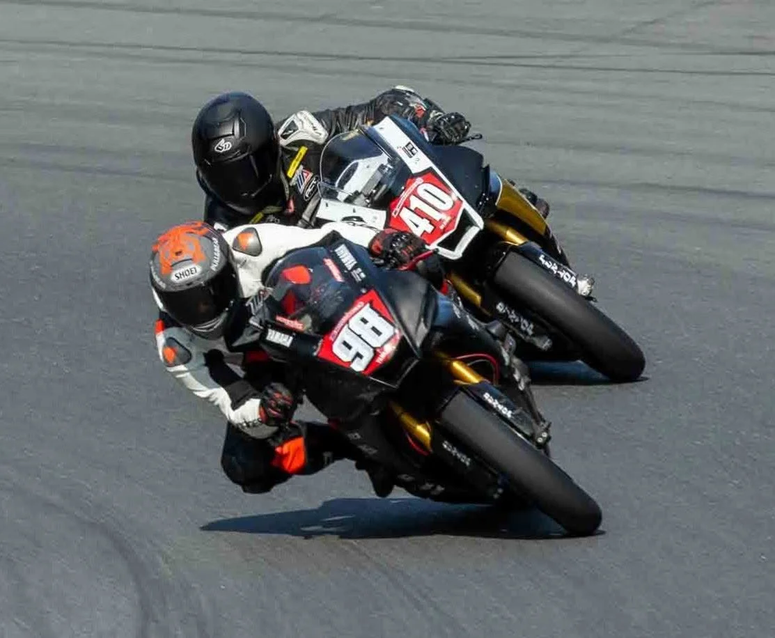 Jeremy Simmons on number 98 leading another rider through a corner on a road race track