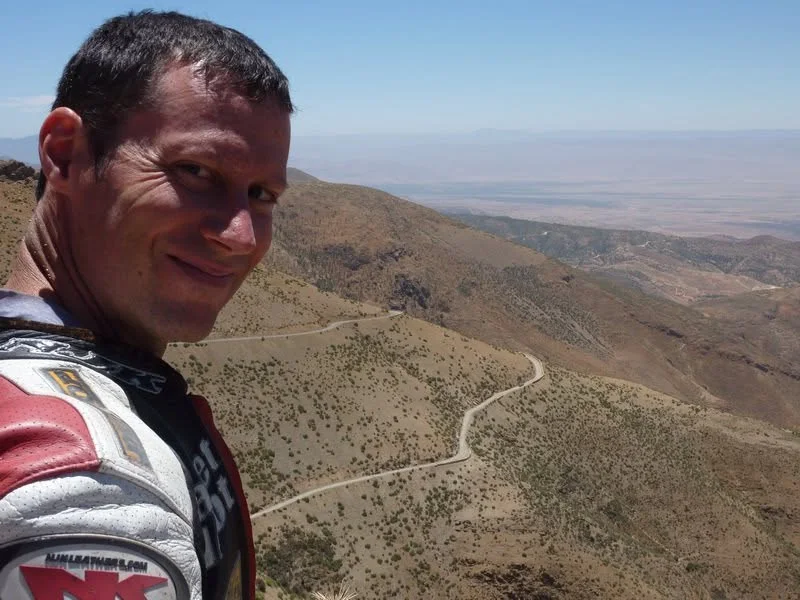 Jeremy Simmons smiling above a winding mountain road in Morocco