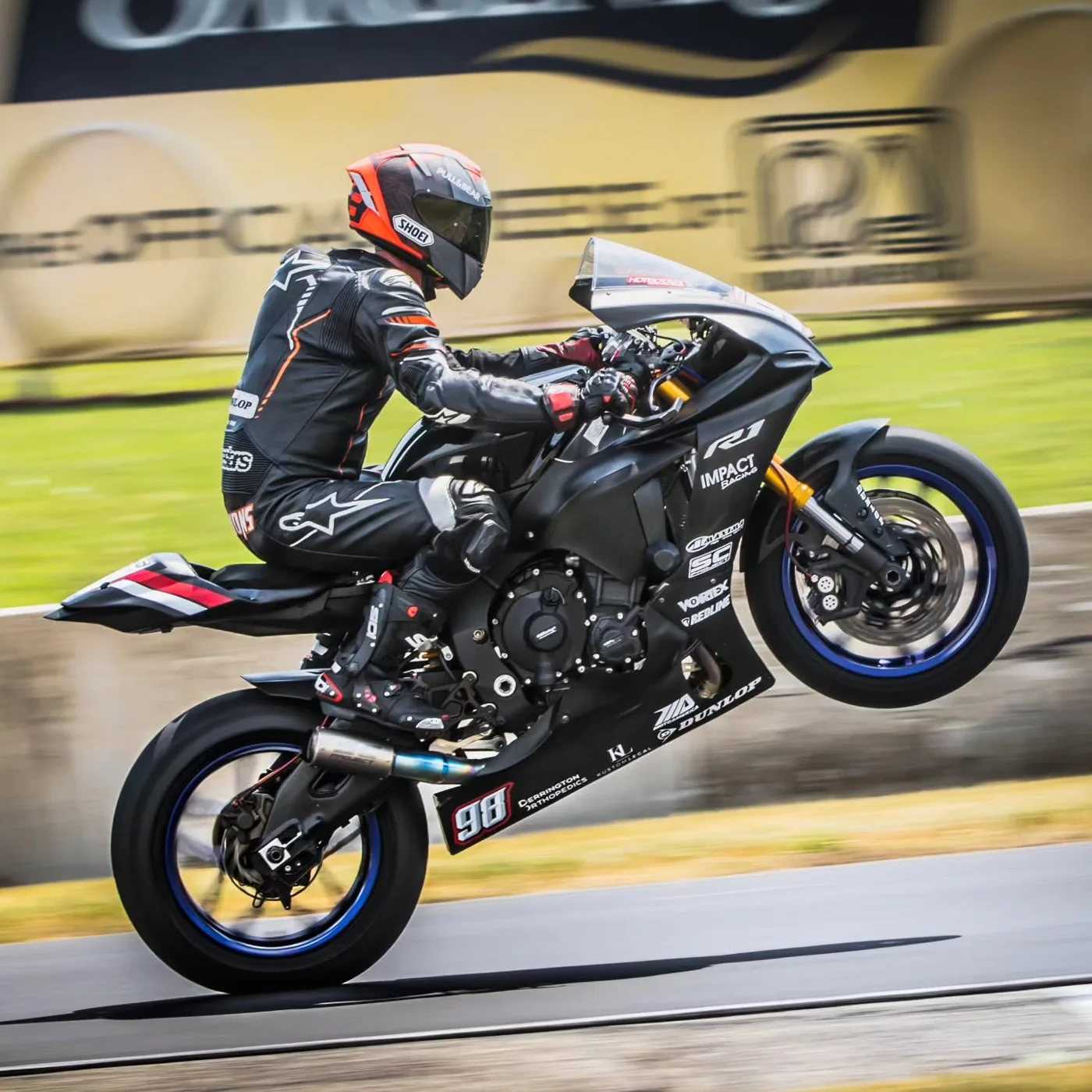 Jeremy Simmons wheelieing a black sports bike on a race track
