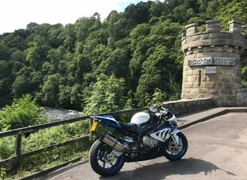 White BMW S 1000 RR parked beside the tower of the Old Craigellachie Bridge