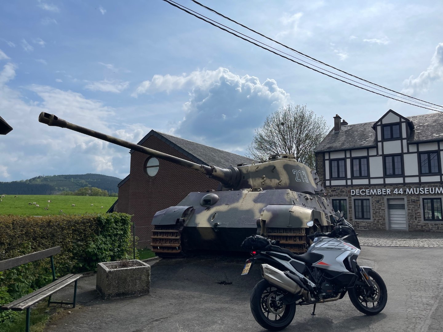 KTM 1290 Super Adventure parked in front of the Tiger II 213 tank monument at La Gleize, with the December 44 Museum behind