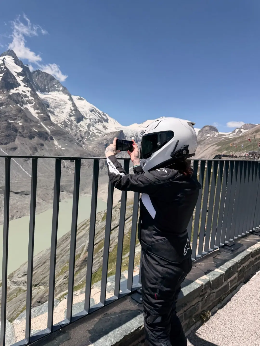 A rider taking a photo of the glacier view from the terrace railing at Kaiser-Franz-Josefs-Hoehe