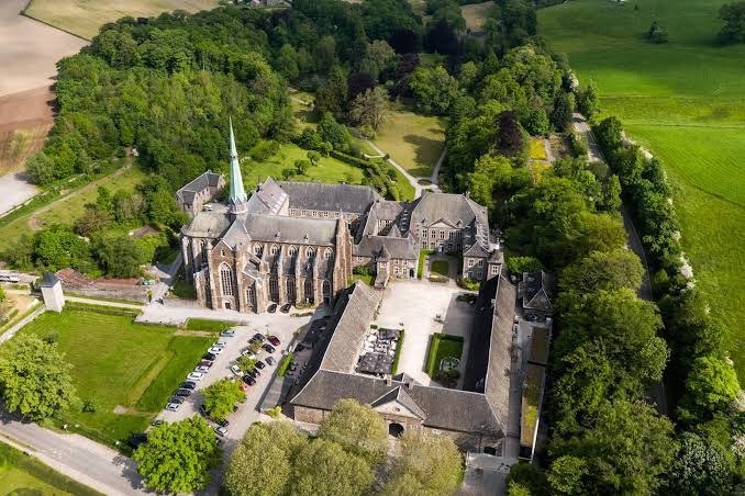 Aerial view of Abbaye du Val-Dieu near Aubel, its church and courtyards surrounded by woodland and green fields