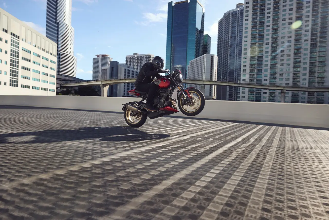 Real photo of a rider lifting the front wheel on the 2026 Triumph Trident 800 against a city skyline
